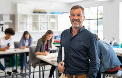 Smiling teacher standing in his classroom